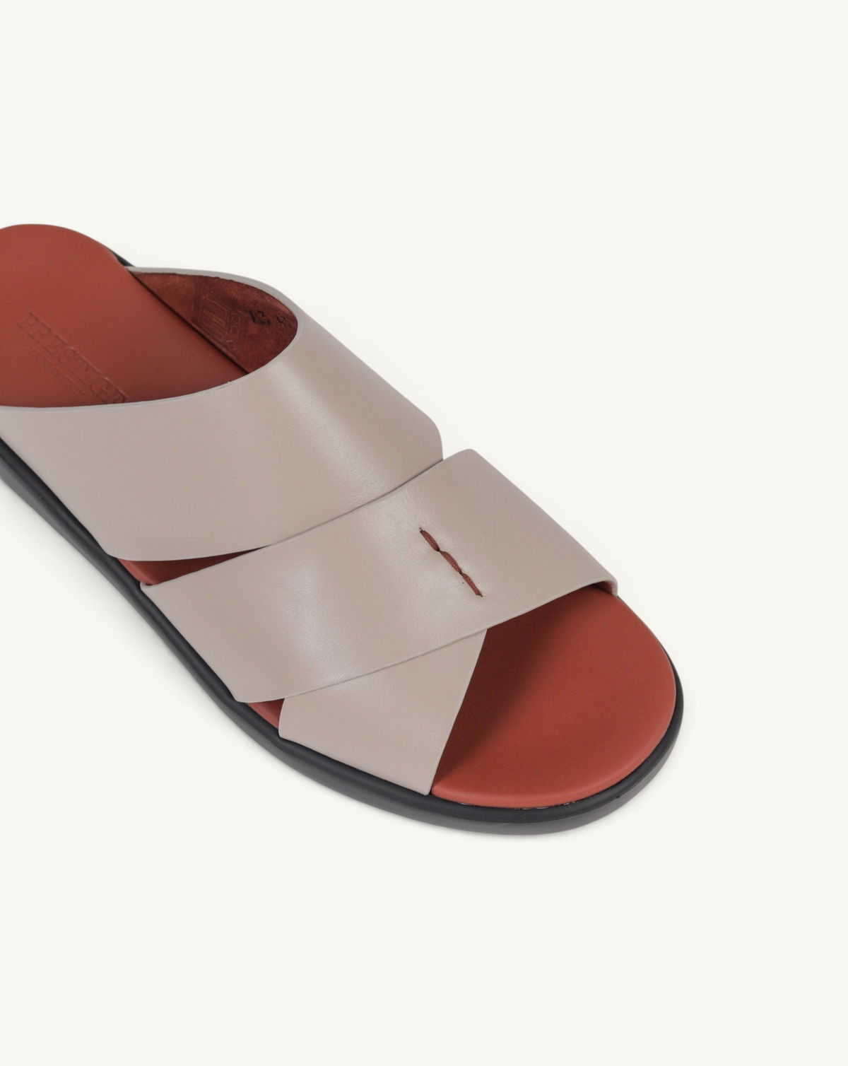 Prestige taupe soft nappa calf leather slide sandals with a crisscross strap design and a contrasting red footbed.