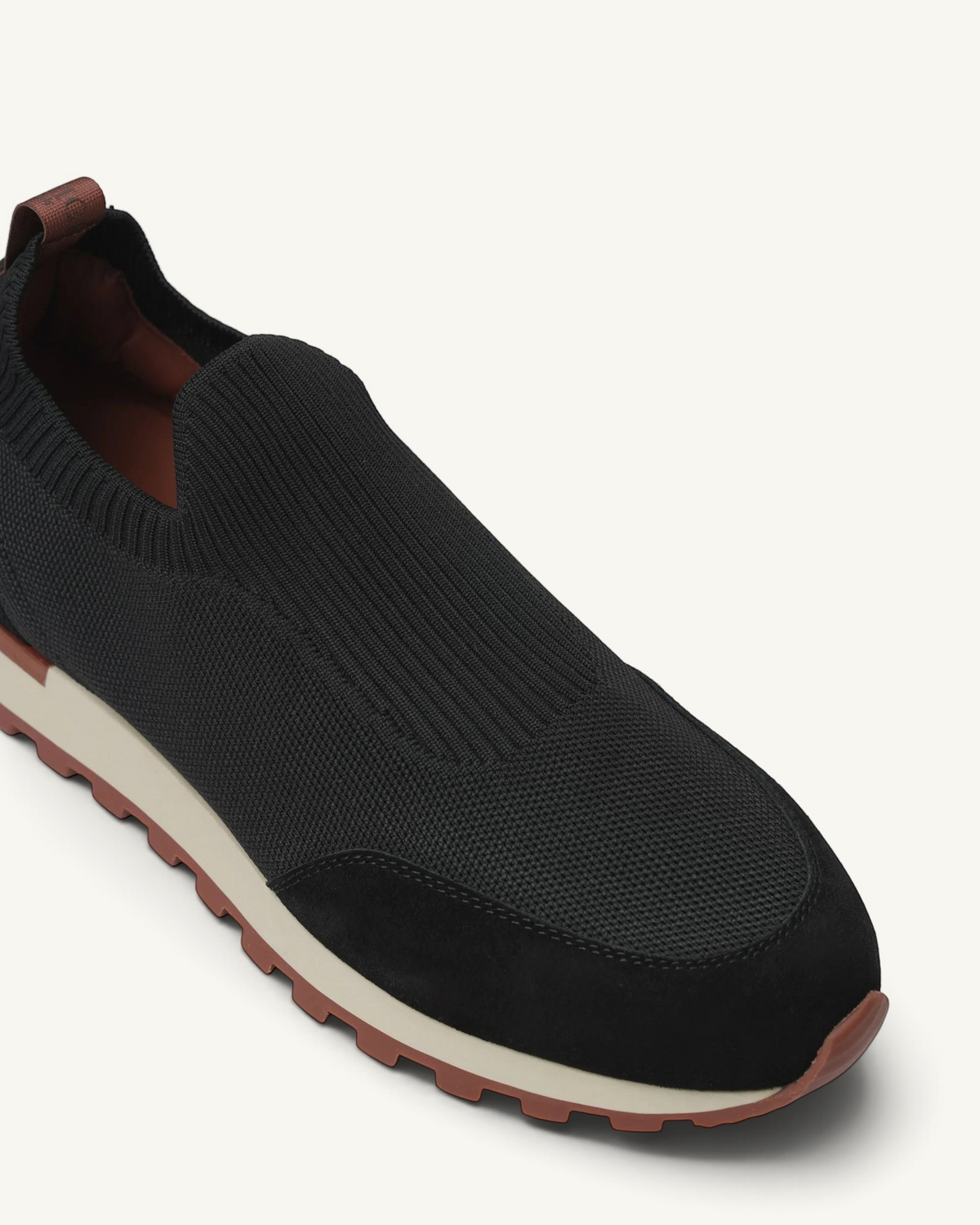 Prestige black slip-on sneakers featuring a breathable knit upper, suede toe cap, and a lugged rubber sole.