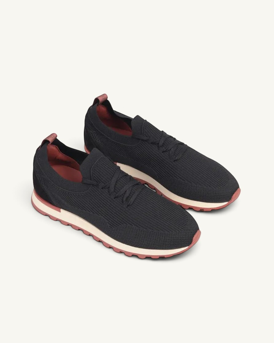 Prestige Flexy Lux Walk black knit sneakers with a white midsole and rust-colored tread and heel tab.