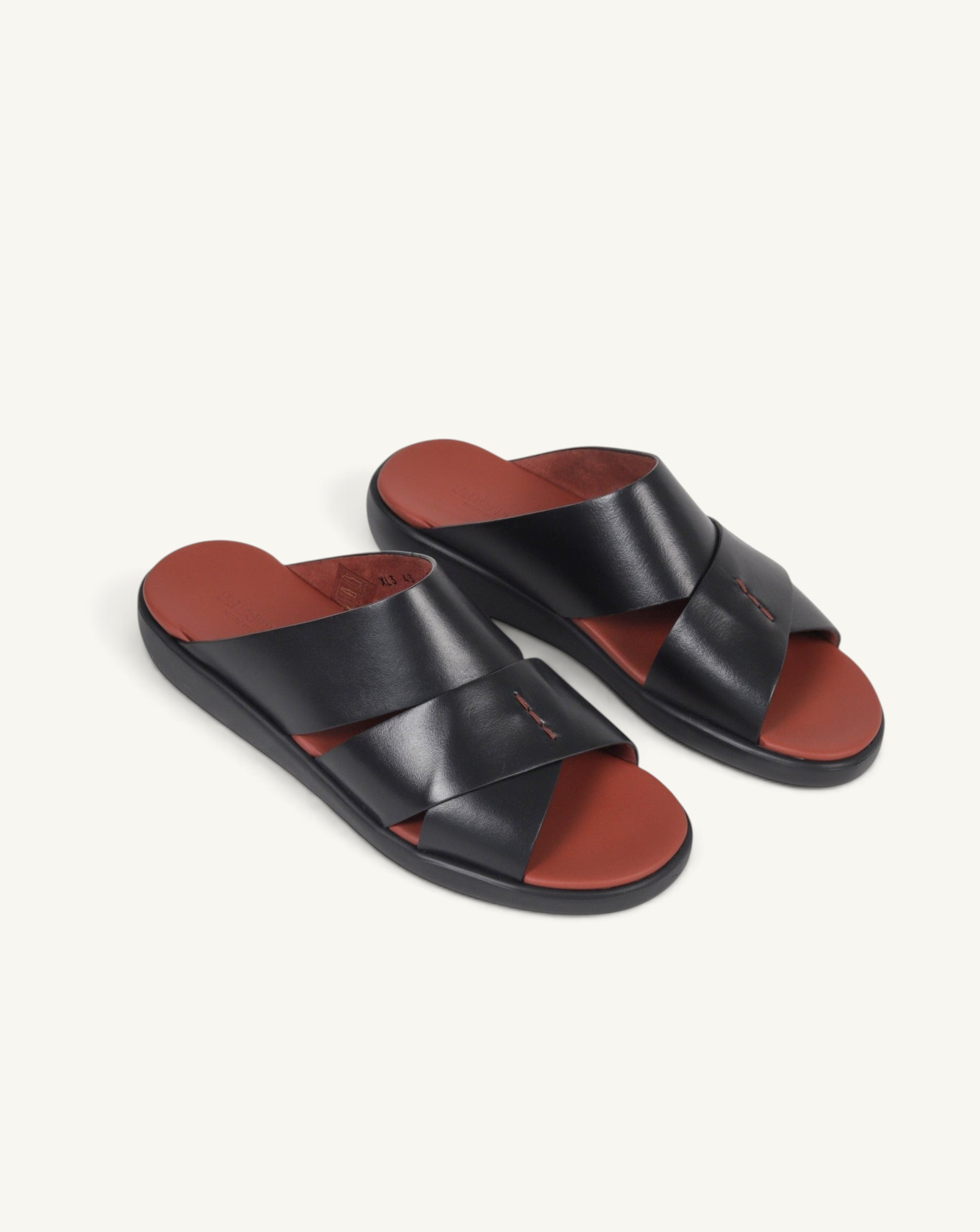 Prestige black soft nappa calf leather slide sandals with a contrasting rust-coloured footbed and crisscross straps.