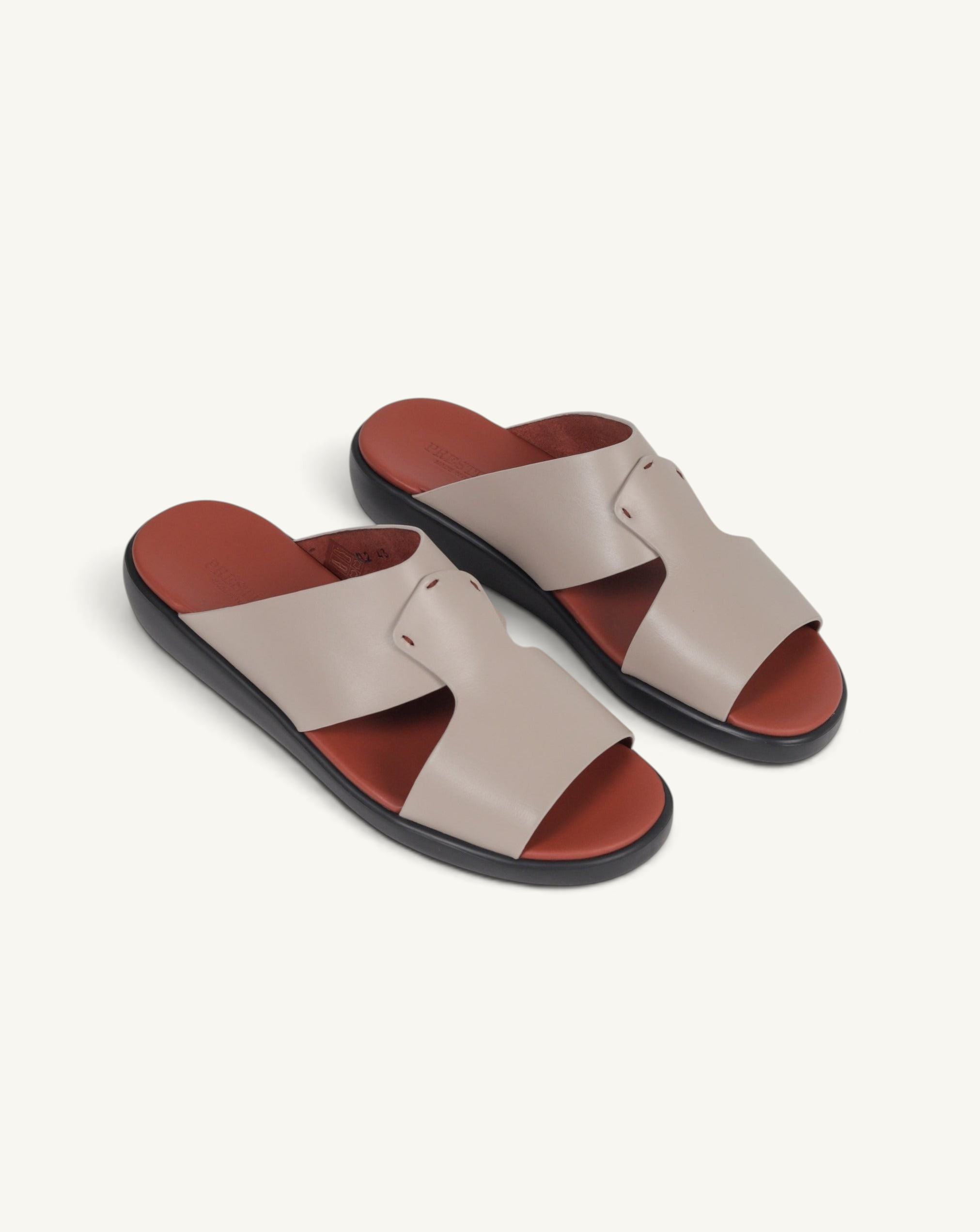 Prestige taupe soft nappa calf leather slide sandals with a contrasting rust-colored footbed and black sole.