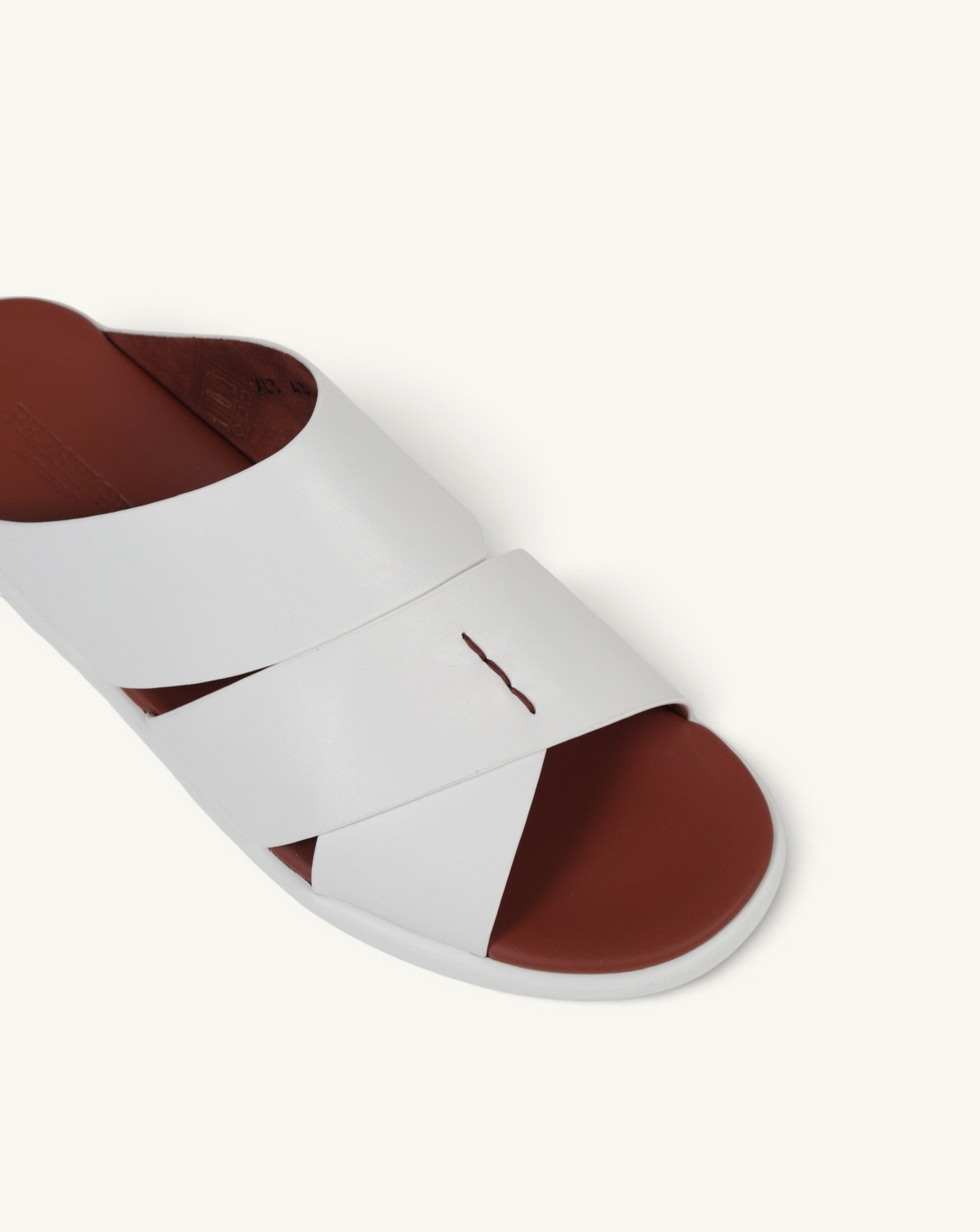 Prestige white soft nappa calf leather slide sandals with a comfortable brown footbed and crisscross strap design.