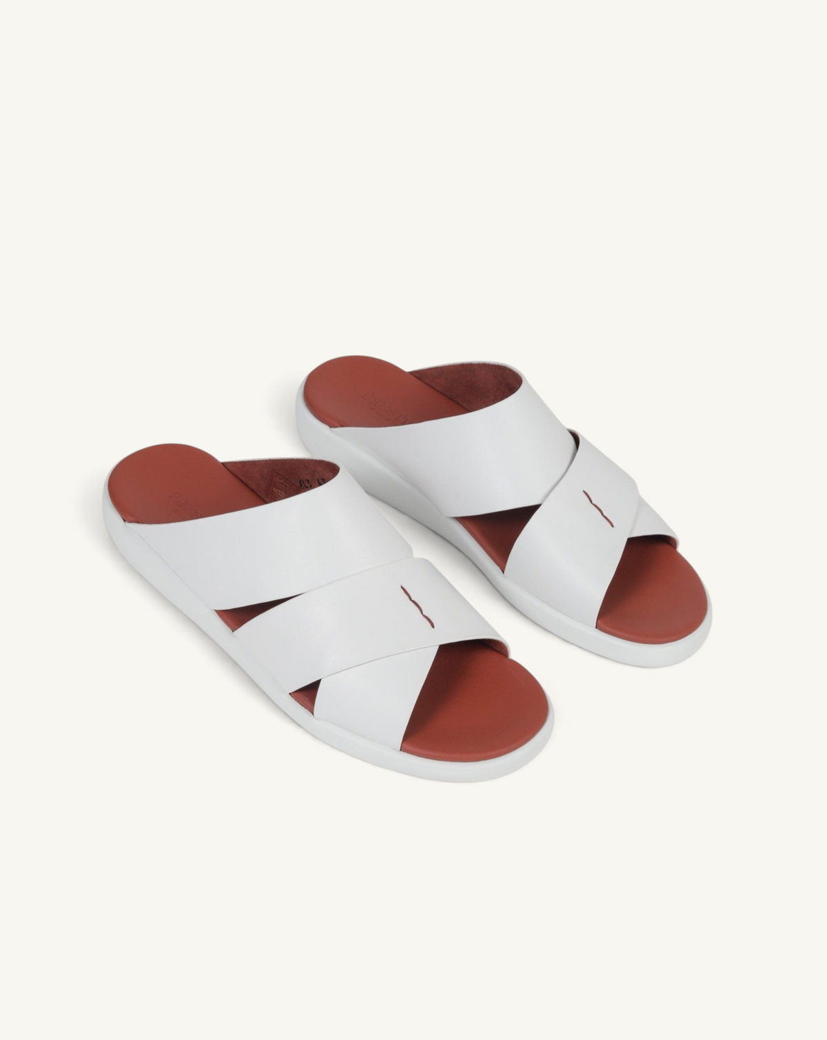 Prestige white soft nappa calf leather slide sandals with a comfortable brown footbed and crisscross strap design.